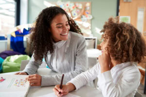 Young smiling woman teacher demonstrating the types of aba therapy to her child student.