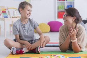 Boy with therapist after parents deciding ABA Therapy vs CBT.